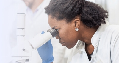 Pesquisadora utilizando microscópio em laboratório para pesquisa científica