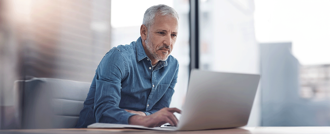 Mann mittleren Alters arbeitet am Laptop