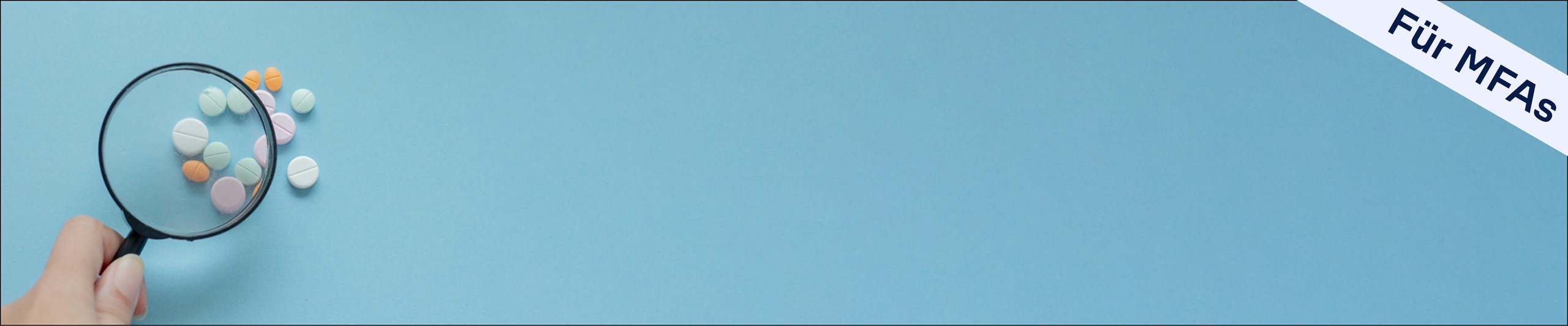 Lupe und bunte Tabletten vor hellblauem Hintergrund
