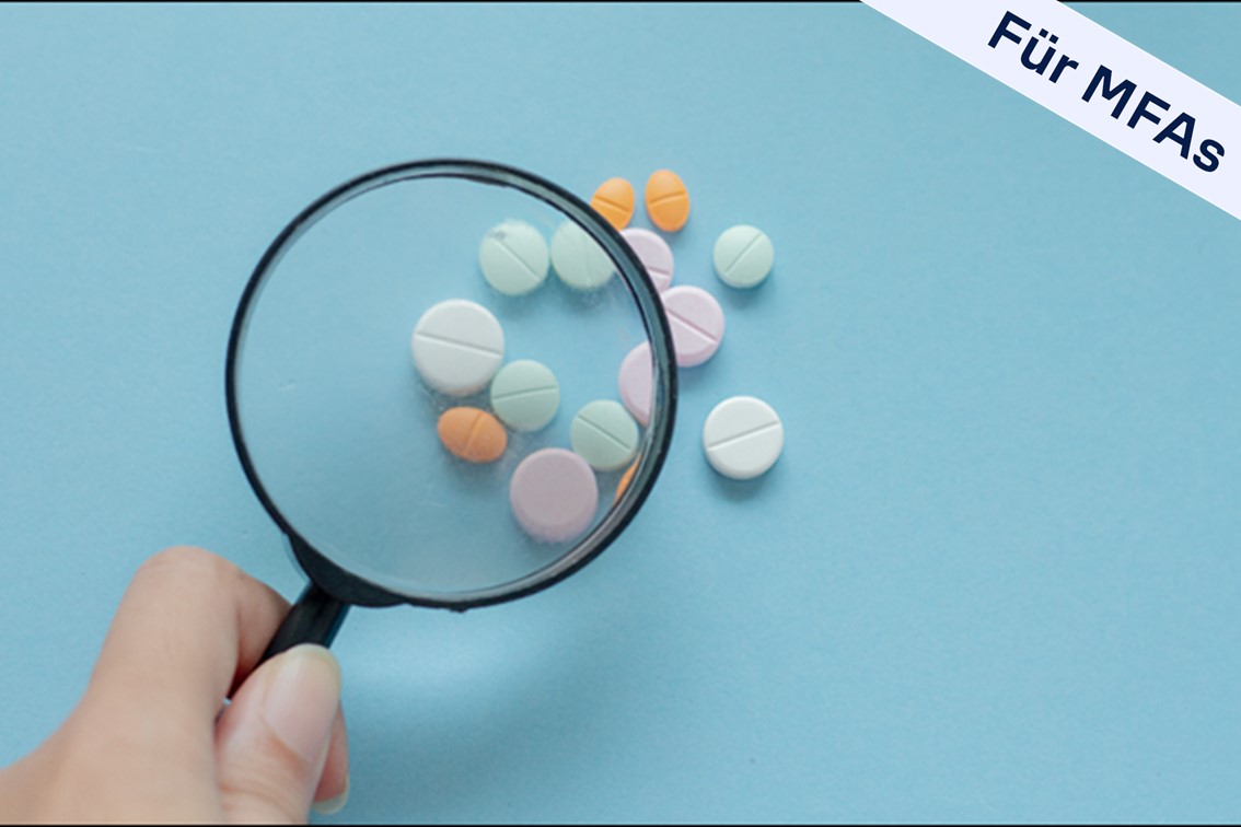 Lupe und bunte Tabletten vor hellblauem Hintergrund