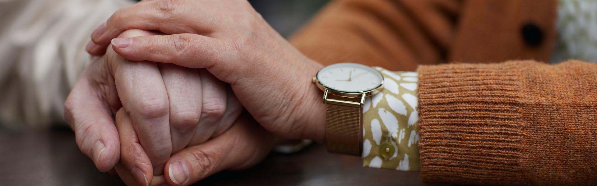 Symbolbild: Zwei ältere Personen halten Ihre Hände auf einem Tisch.
