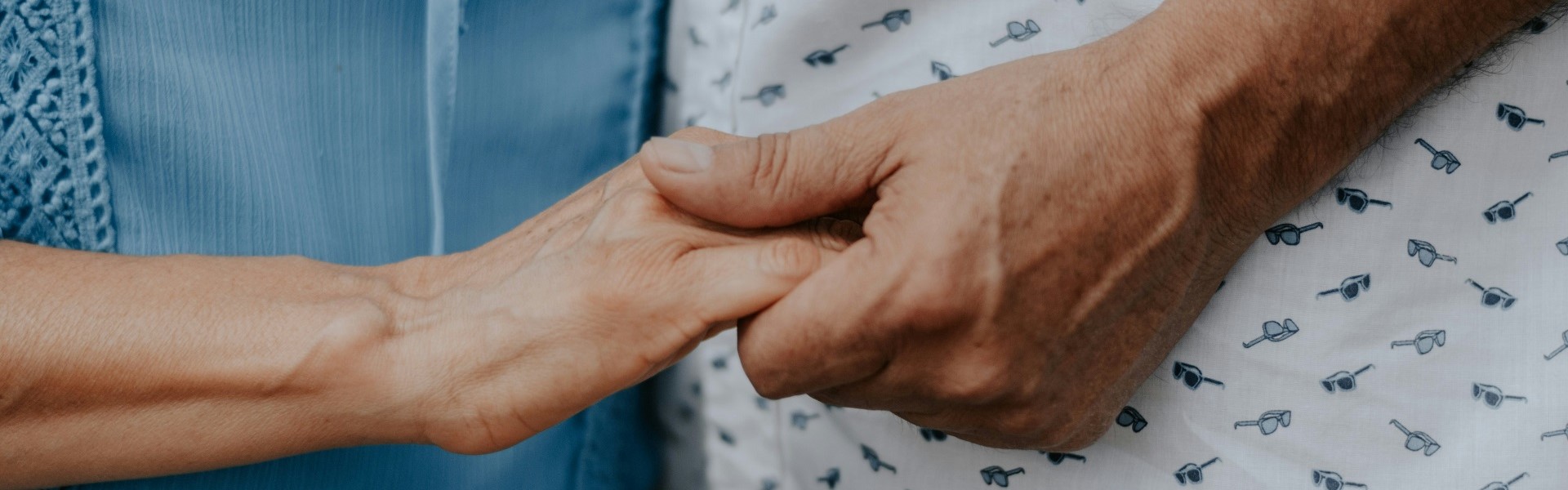 Symbolbild: Zwei ältere Personen halten Ihre Hände auf einem Tisch.