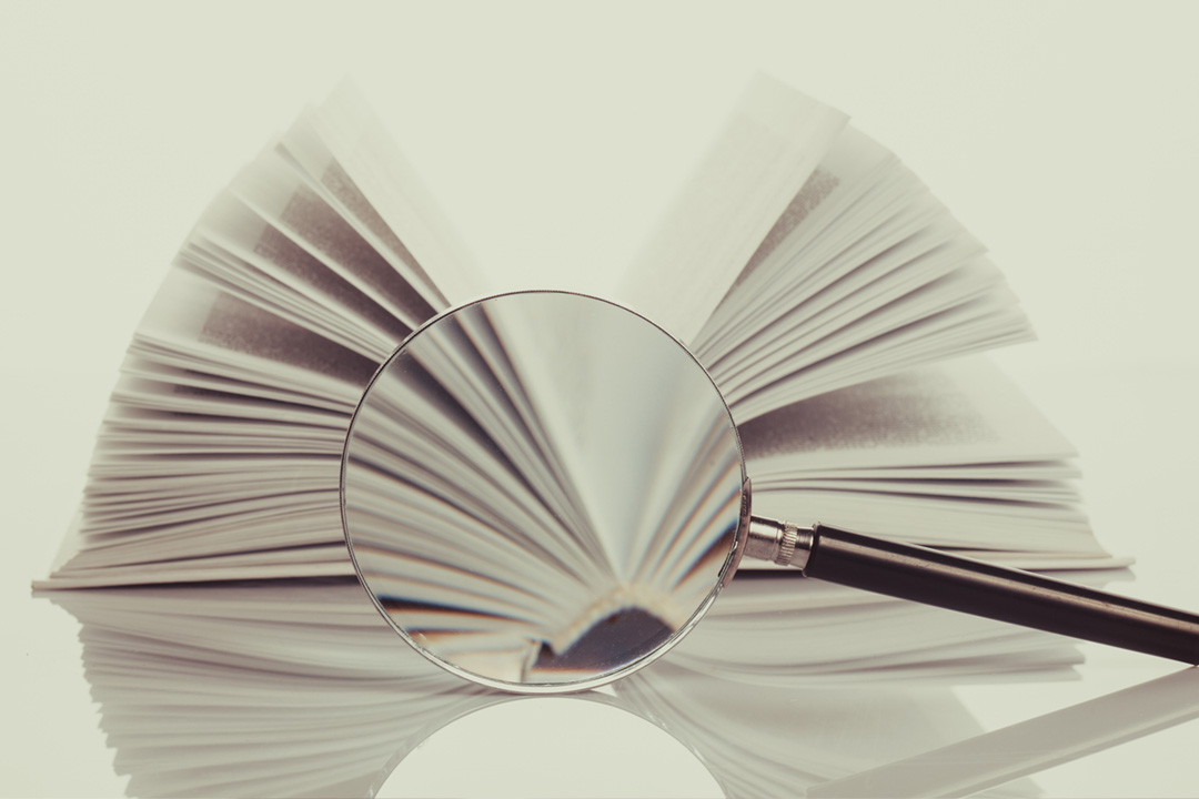 Aufgeschlagenes Buch mit Lupe