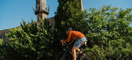 Ciclista di città costeggia un'area verde