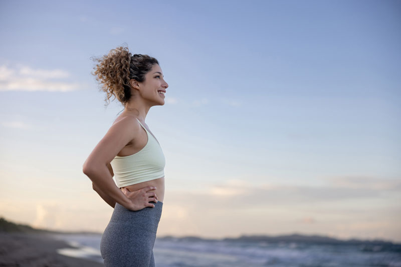 Donna in tenuta sportiva sulla spiaggia al tramonto