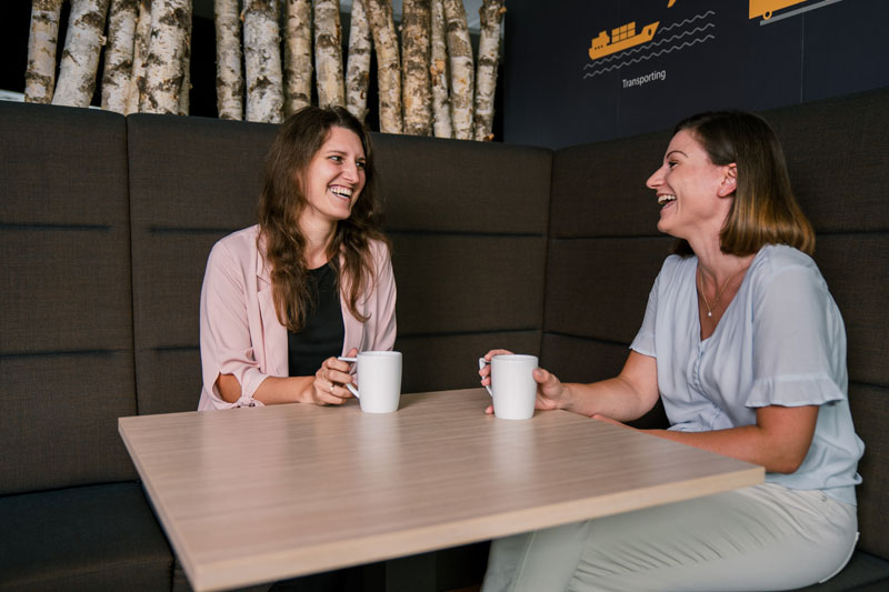 Due ragazze sorridenti chiacchierano in un caffè
