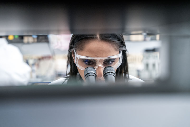 Ricercatrice che osserva attraverso un'apparecchiatura