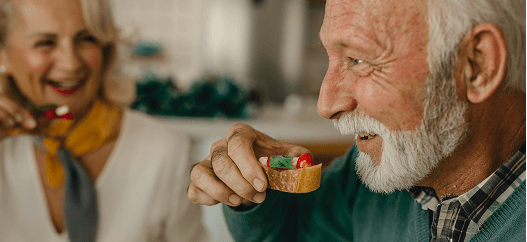 Anziano mangia una bruschetta mentre la moglie ride