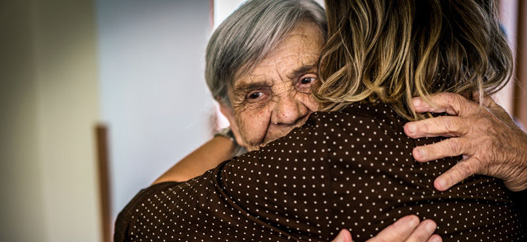Abbraccio tra un anziano e un'altra persona di spalle