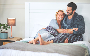 Coppia sorridente si abbraccia a letto in pigiama