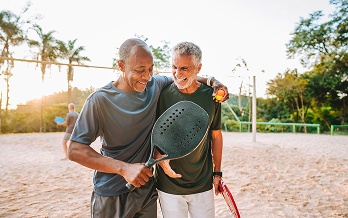 Amici senior giocano a beach tennis al tramonto