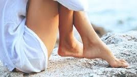 Kvinna sitter i sand på en strand