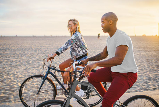 Man och kvinna cyklar längst med stranden
